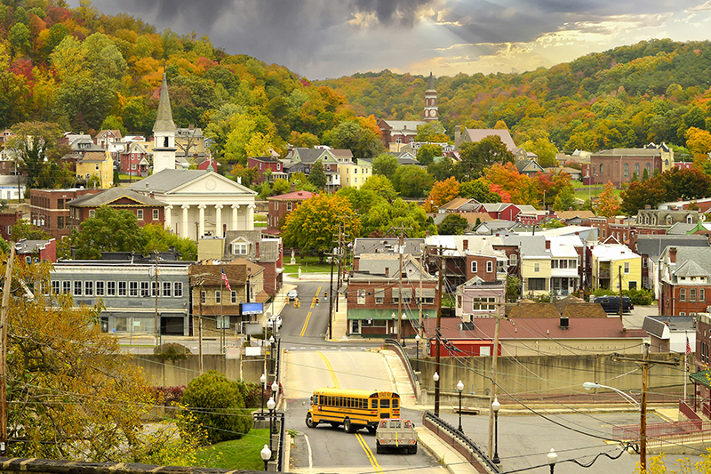 Wide shot of a small town that includes streets, a schoolbus, a church, and many municipal buildings