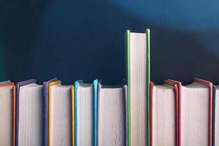 colorful books lined up infront of a dark blue background