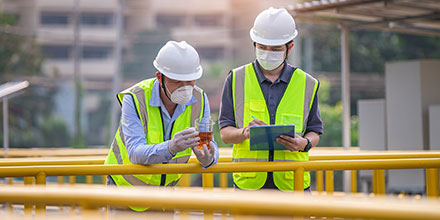 A couple of public entities employees testing water while looking over a tablet