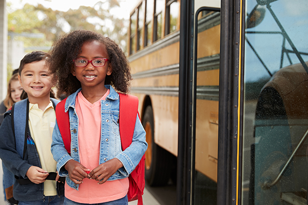 students standing in front of a school bus