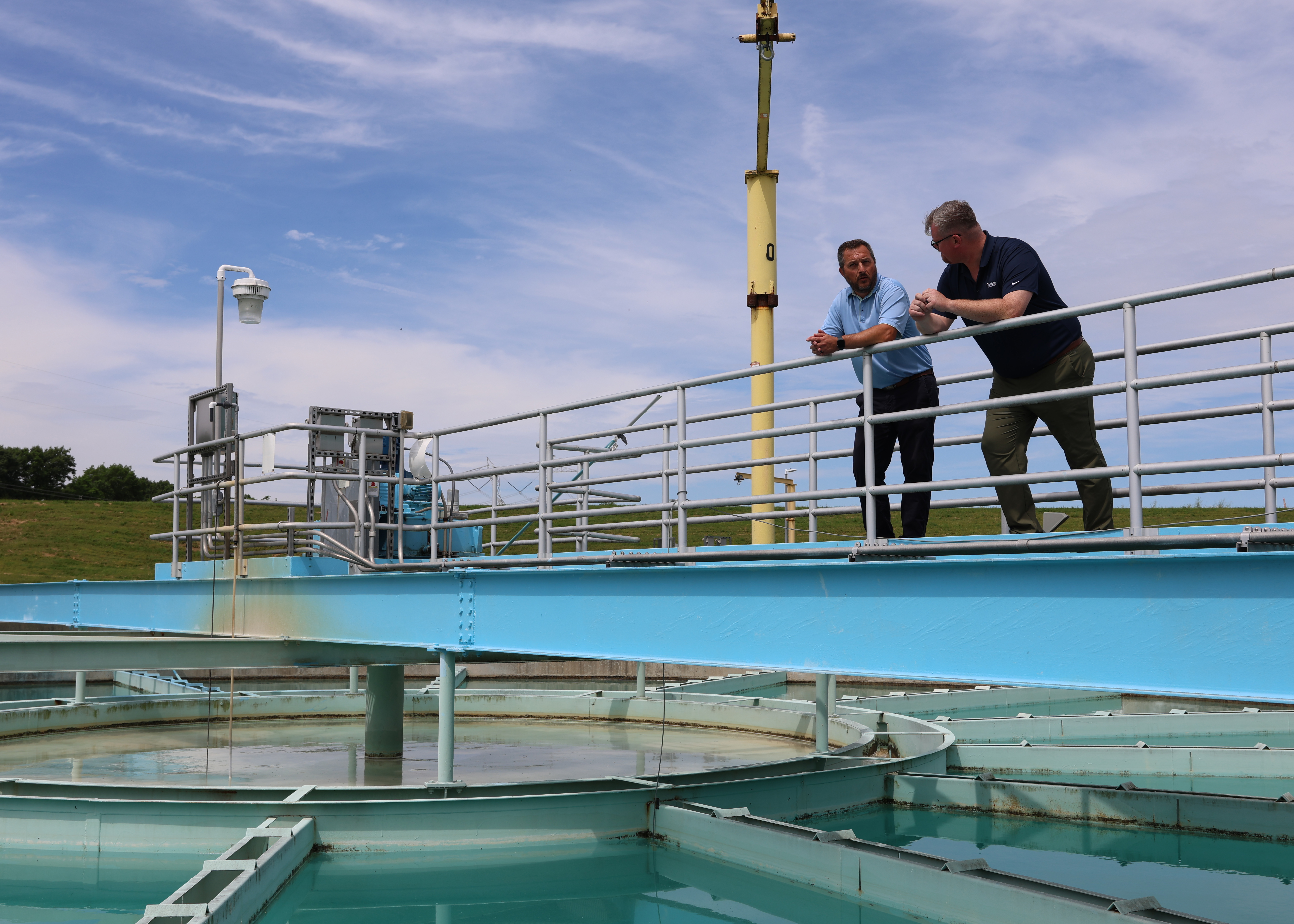 A client and a risk consultant talking while leaning on a railing overlooking a water facility