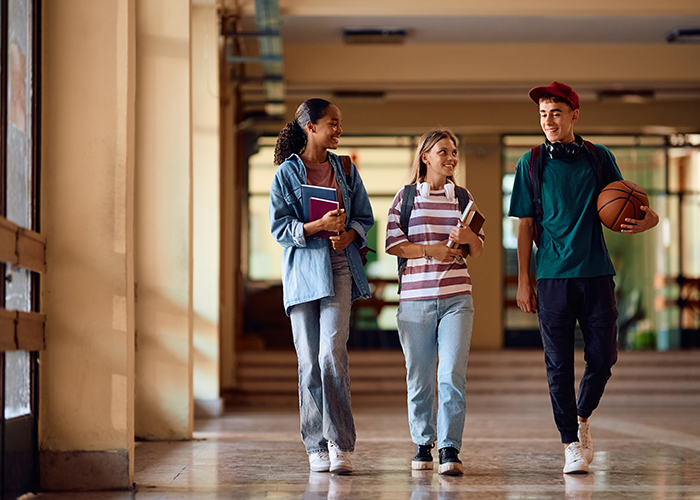 School kids walking down hall with books and smiling